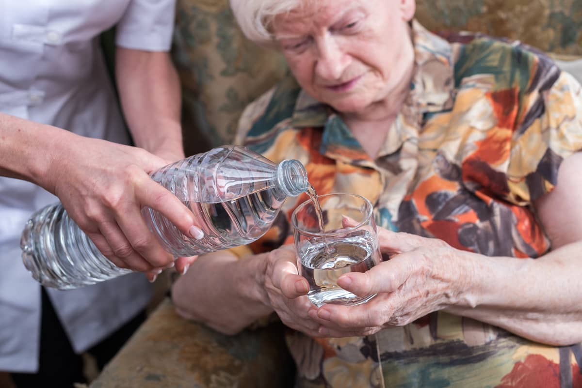 Someone pouring an elderly woman some water