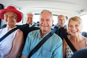A group of seniors smiling in the backseat of a van