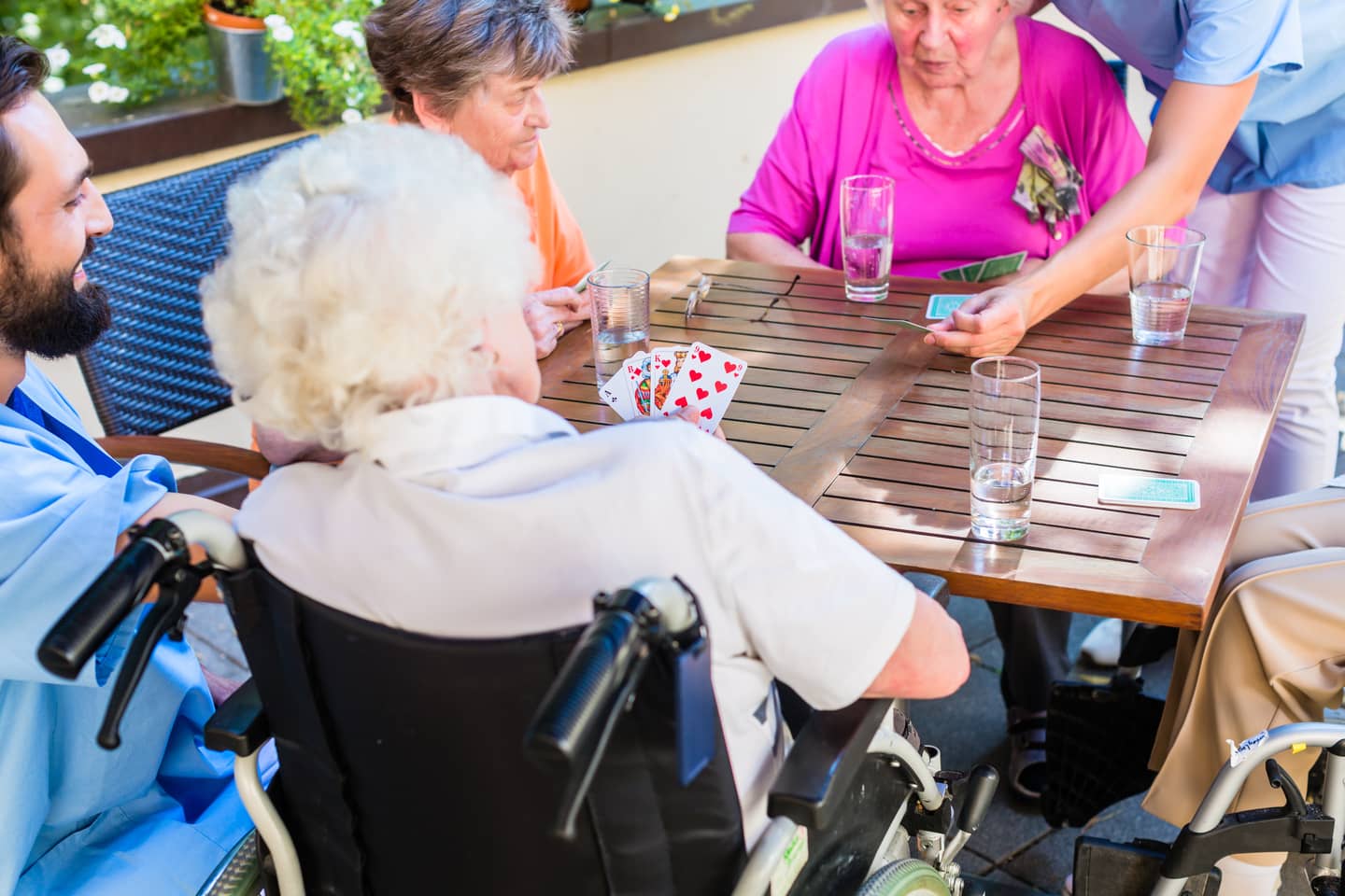 Home care aides helping seniors play cards