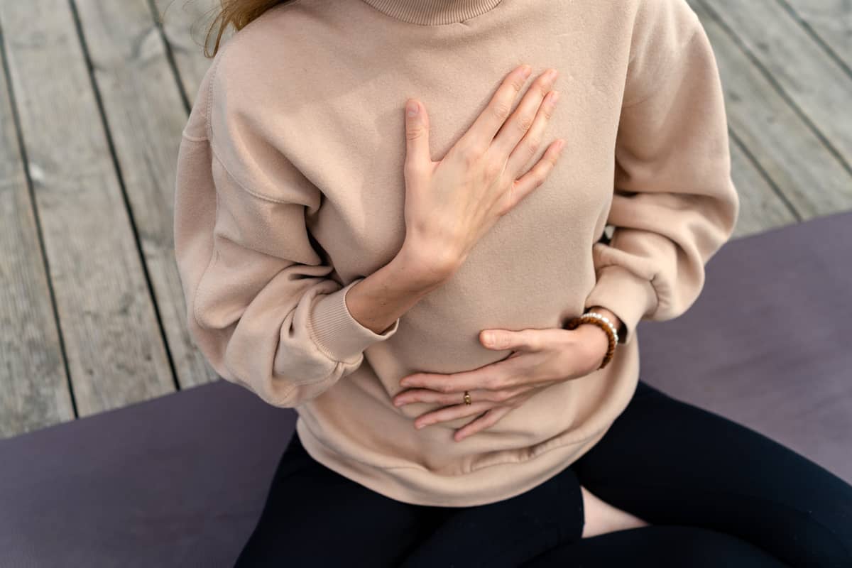 A woman sitting breathing with her hands on her chest