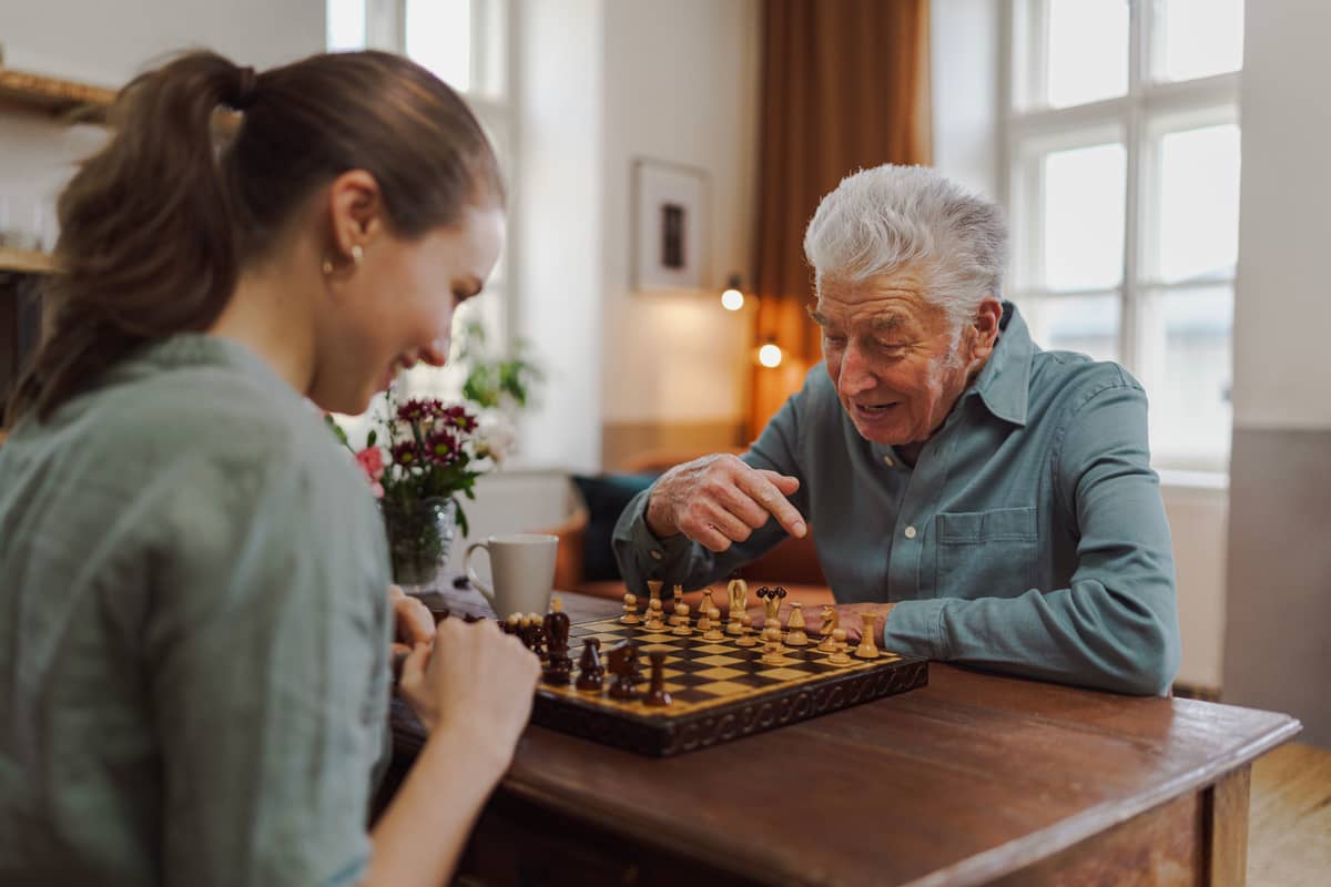 A caregiver playing chess with a senior man