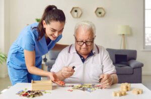 A caregiver is helping a senior man with a puzzle