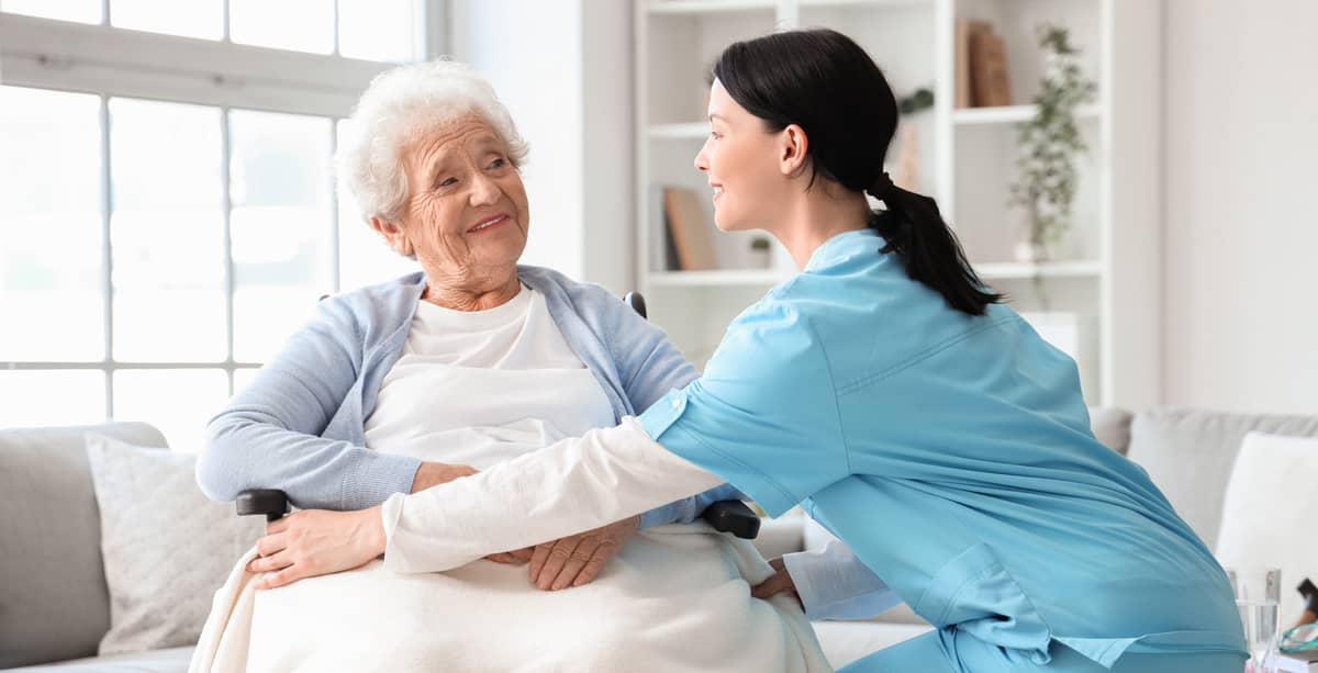 A caregiver helping a senior woman in a wheelchair