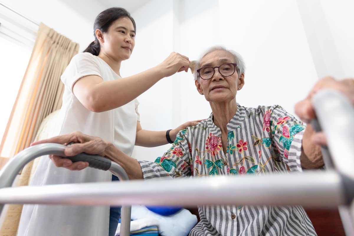 A caregiver brushing the hair of a senior woman