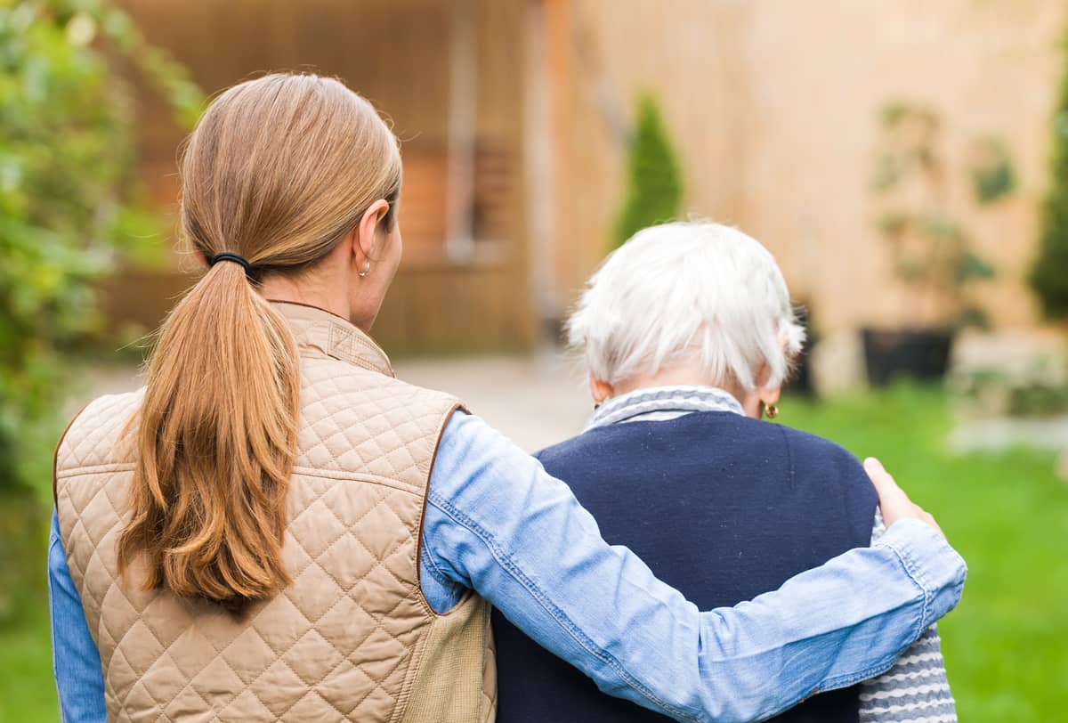 A woman helping an elderly man get into his house
