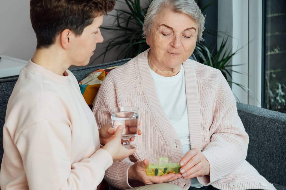 A caregiver helping a senior woman with their meds