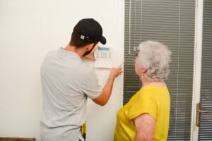 A man setting up a security system for a senior woman