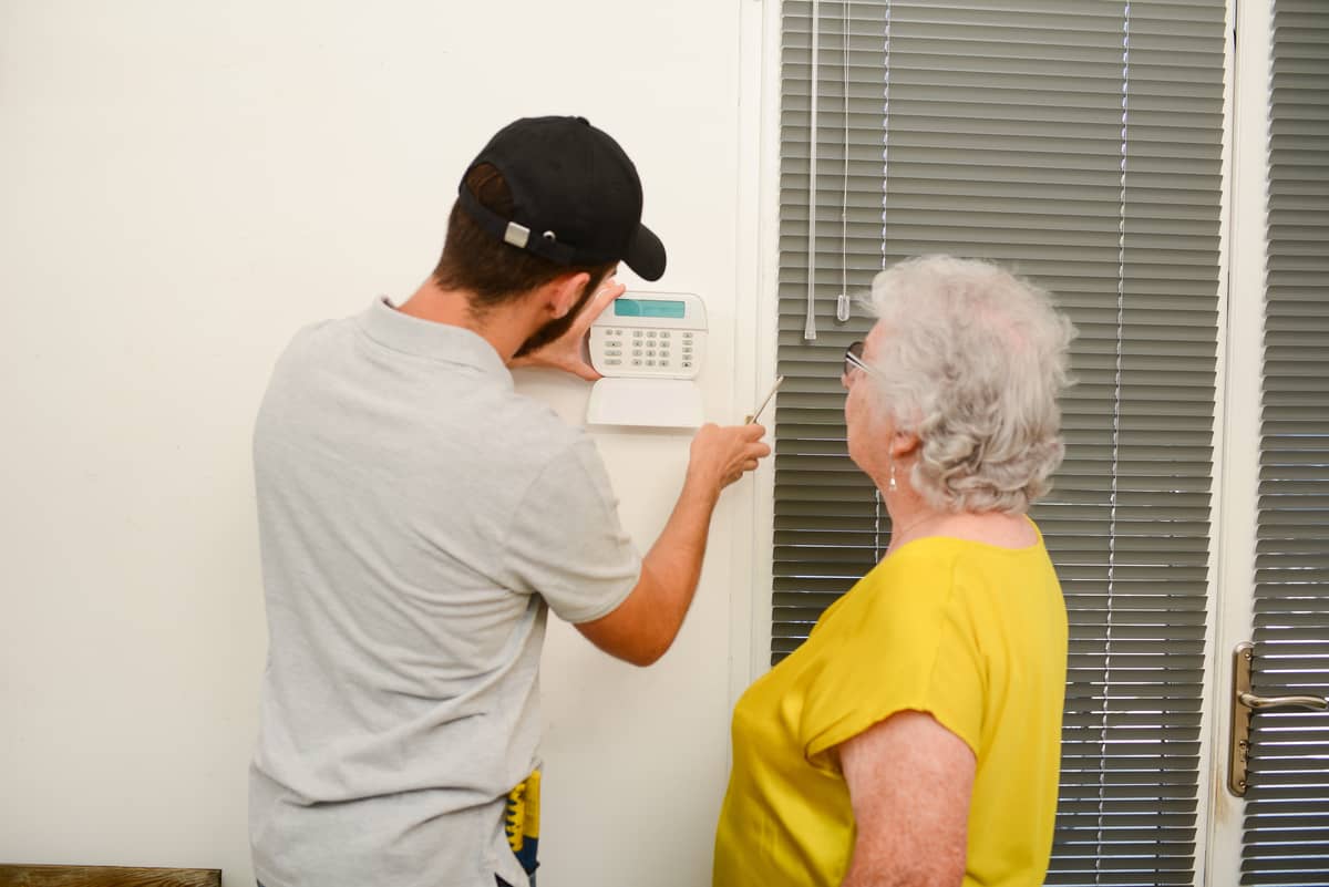 A man setting up a security system for a senior woman