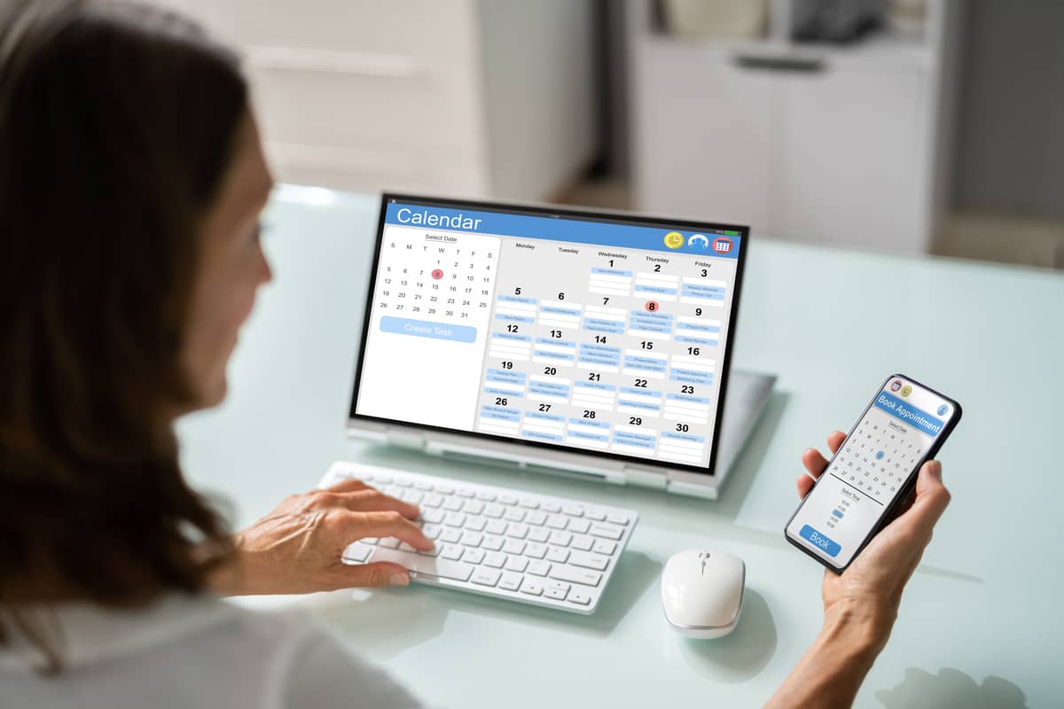 An appointment liaison setting appointments with a calendar open on phone and laptop