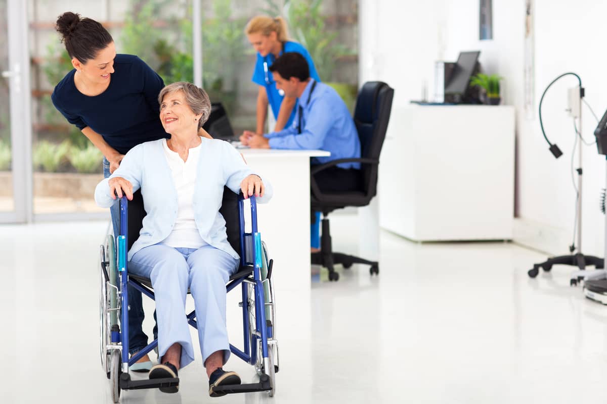 A woman helping a senior woman in a wheelchair at a hospital