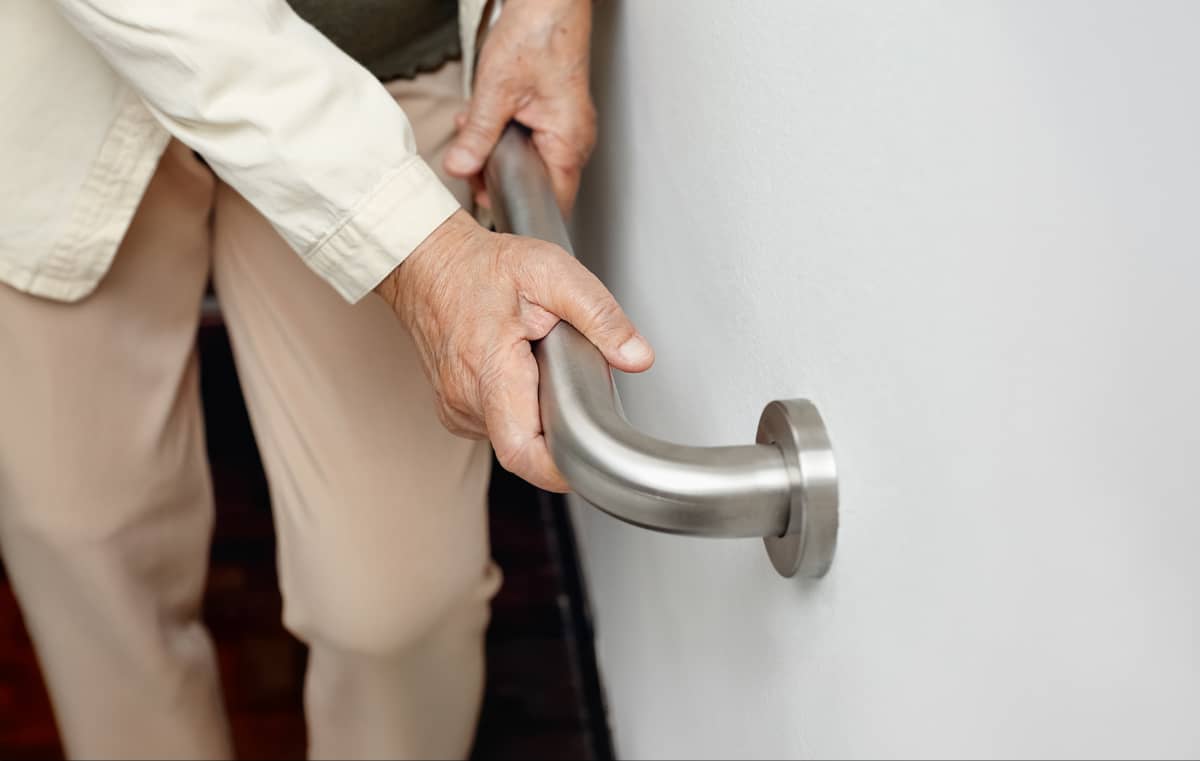 A senior woman holding on to a handrail