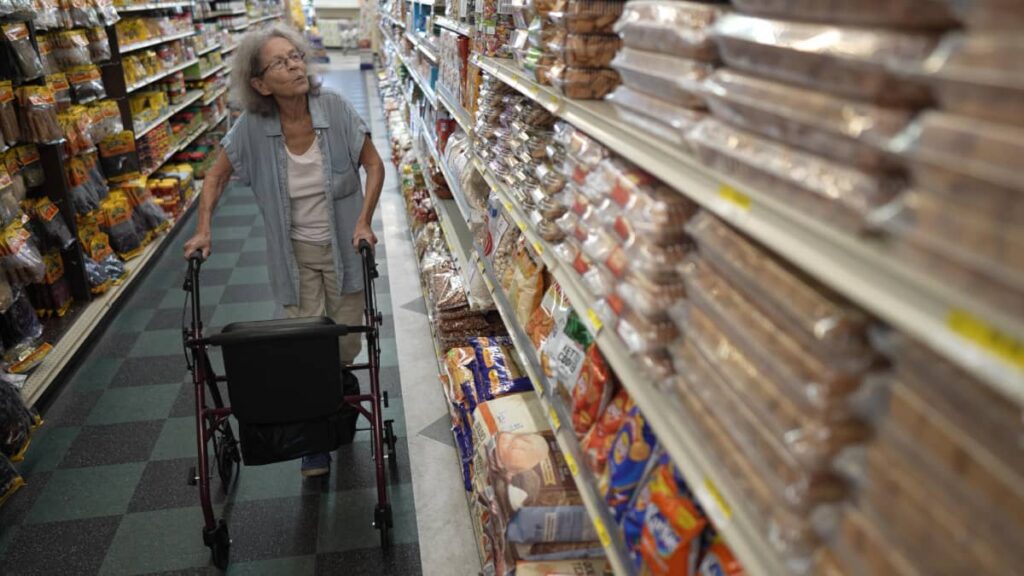 A senior woman using a walker in a grocery aisle