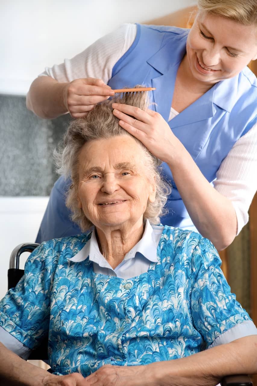 A home caregiver brushing a senior woman's hair