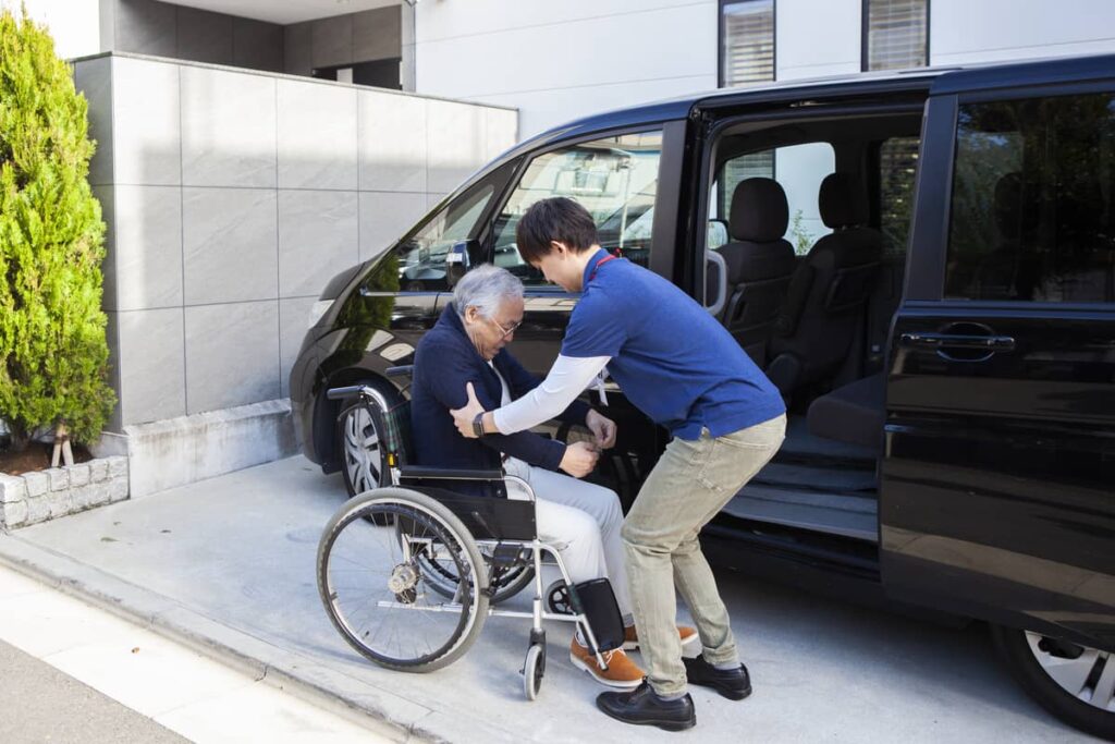A caregiver helping a senior in a wheelchair into a car