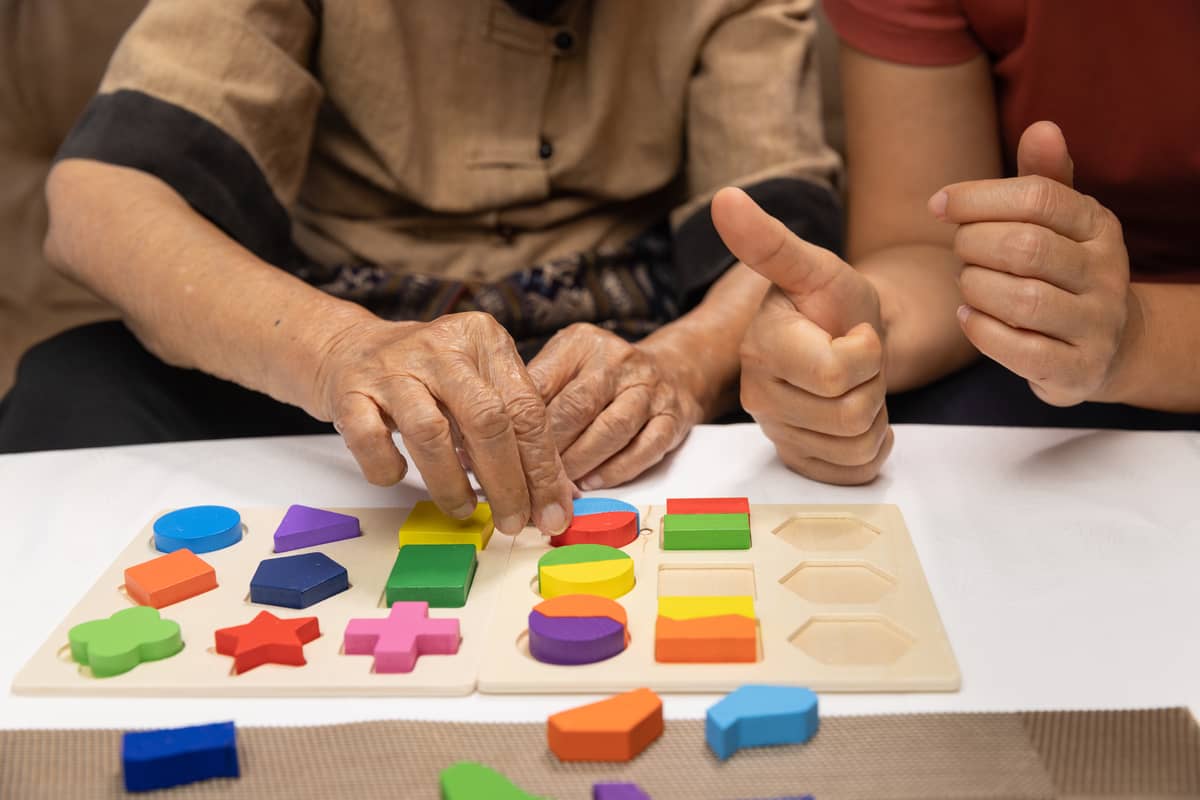 Showing someone helping a senior do a puzzle